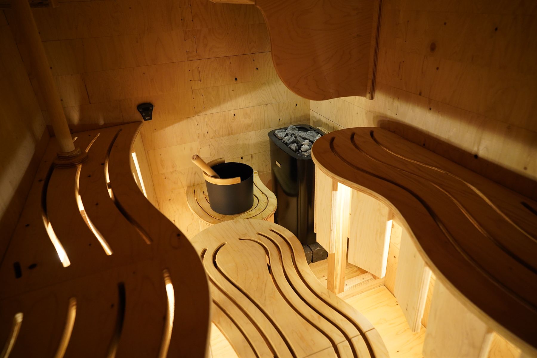ocomori sauna の内観 — 波形ベンチとフィンランド製ストーブ